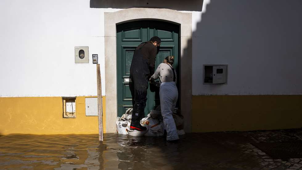 Populares tentam entrar numa casa, numa rua inundada na zona ribeirinha de Alcácer do Sal, Setúbal, 06 de fevereiro de 2026. Treze pessoas morreram em Portugal desde a semana passada na sequência da passagem das depressões Kristin e Leonardo, que provocaram também muitas centenas de feridos e desalojados.. JOSÉ SENA GOULÃO/LUSA