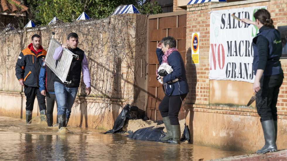 epa12730435 People walk in a flooded street due to heavy storms in El Robledo, Ciudad Real, Spain, 12 February 2026.  EPA/Jesus Monroy
