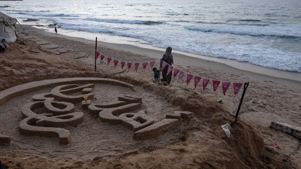 epa12751663 Palestinians observe a sand sculpture bearing the phrase 'Welcome, Ramadan,' created by Palestinian artist Yazeed Abu Jarad, on a beach in Khan Yunis, southern Gaza Strip, 17 February 2026, amid a ceasefire between Israel and Hamas. Abu Jarad was displaced to the south by the war from his home in Beit Lahia, in northern Gaza.  EPA/HAITHAM IMAD