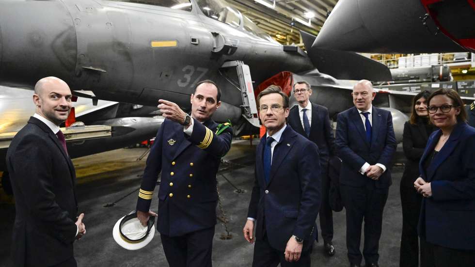 epa12781585 Ship commander Captain Thomas Puga (2-L) guides Swedish Prime Minister Ulf Kristersson (3-L), French Foreign Minister Jean-Noël Barrot (L) and Swedish Foreign Minister Maria Malmer Stenergard (R) among the fighter jets on the hangar deck before the bilateral meeting on the French aircraft carrier Charles De Gaulle (R91) at the quay in the North Port in Malmo, Sweden, 27 February 2026.  EPA/JOHAN NILSSON  SWEDEN OUT