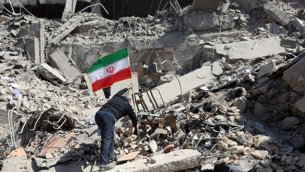epa12794457 An Iranian man places Iran's national flag among the ruins of a damaged police station building in central Tehran, Iran, 04 March 2026. A joint Israeli and US military operation continues to target multiple locations across Iran since the early hours of 28 February 2026.  EPA/ABEDIN TAHERKENAREH