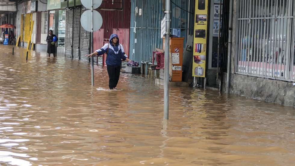 Uma popular caminha por uma rua inundada devido às chuvas na cidade de Maputo, Moçambique, 12 de março de 2026. A cidade de Maputo regista desde a manhã de hoje novas cheias, que condicionam a circulação em várias zonas da capital moçambicana, devido às fortes chuvas, pela segunda vez em menos de uma semana. (ACOMPANHA TEXTO). LINA CEBOLA/LUSA