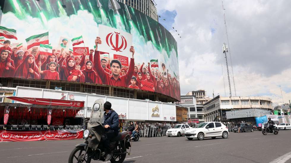 epa12871328 Iranians drive past a large political billboard displaying Iran's national flags at Valiasr Square in Tehran, Iran, 06 April 2026. The US president has given Iran a 48-hour deadline to reach a deal and reopen the Strait of Hormuz.  EPA/ABEDIN TAHERKENAREH