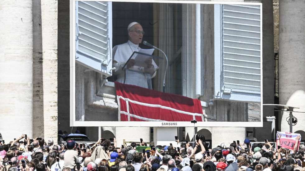 epa12967042 Faithful stand next to a screen showing Pope Leo XIV as he leads his Regina Caeli prayer from the window of his office overlooking Saint Peter's Square in Vatican City, 17 May 2026.  EPA/RICCARDO ANTIMIANI