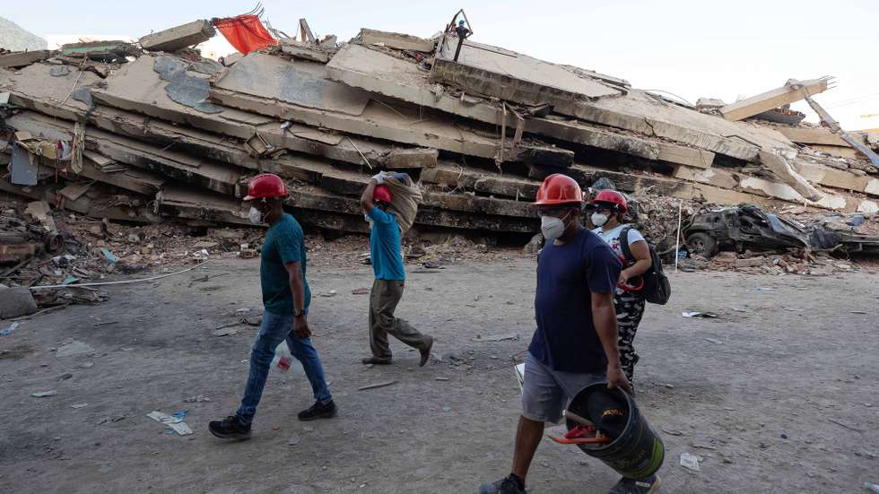 epa13072580 People walk past the rubble of a building in La Guaira, Venezuela, 29 June 2026. National and international rescue teams continue their efforts among the ruins of buildings in the coastal state of La Guaira, north of Caracas, the epicentre of devastation caused by 7.2- and 7.5-magnitude earthquakes, where logistics centres for international teams have been set up.  EPA/RONALD PENA R