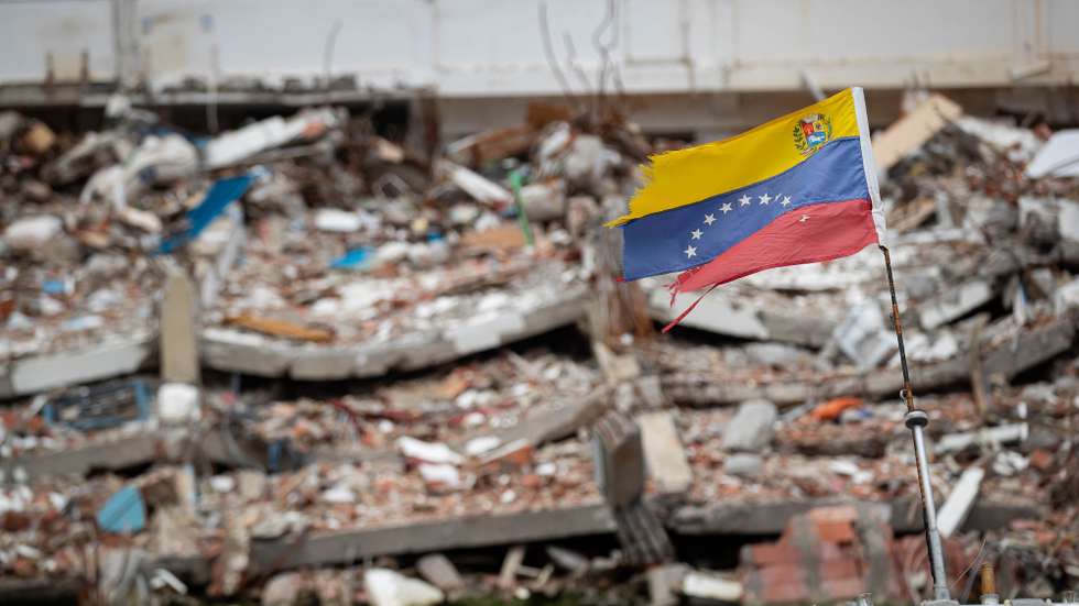 epa13158506 A Venezuelan flag flutters in the wind amid debris in La Guaira, Venezuela, 09 August 2026. La Guaira is the state hardest hit by the two earthquakes that struck Venezuela on 24 June.  EPA/RONALD PENA R