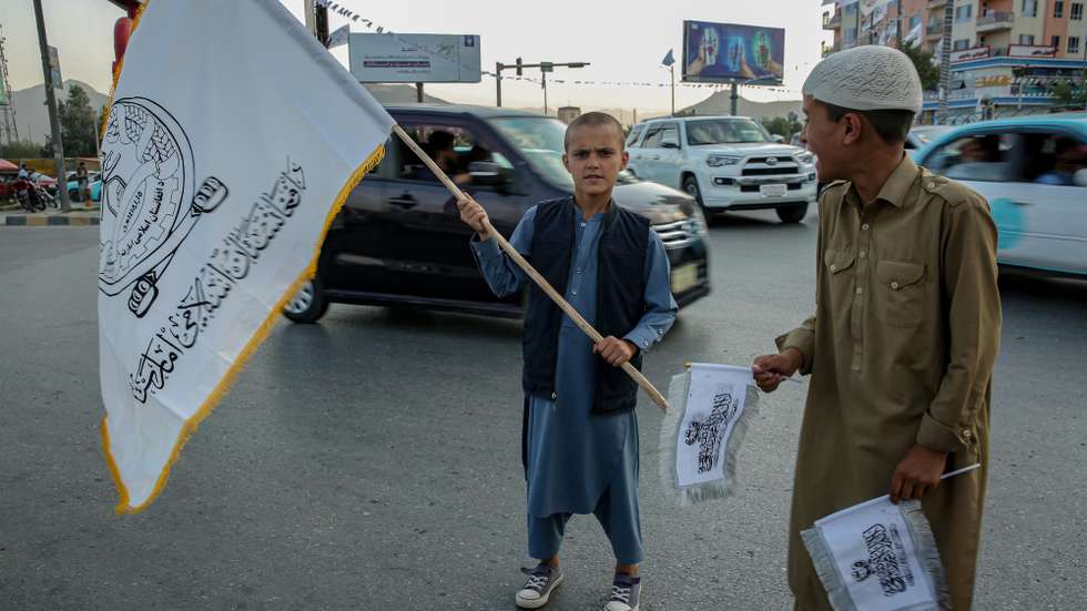 epa13167545 Afghan boys sell flags of the Islamic Emirate of Afghanistan ahead of the fifth anniversary of the Taliban's return to power in Kabul, Afghanistan, 13 August 2026. Extensive preparations are underway in Kandahar, with pro-government slogans displayed across the city ahead of the fifth anniversary of the Taliban's return to power on 15 August 2021.  EPA/SAMIULLAH POPAL