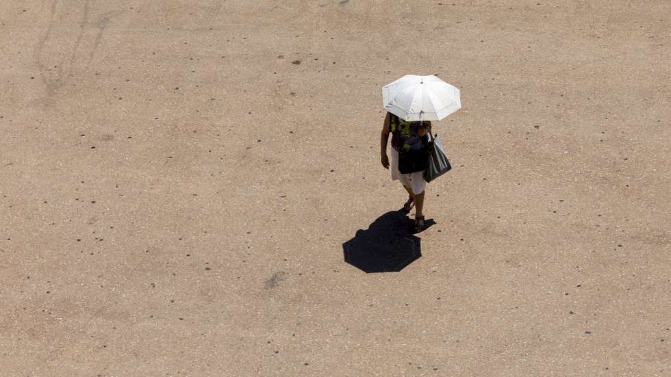 epa12215058 A passer-by holding an umbrella for sun protection walks in Valencia, eastern Spain, 04 July 2025. Despite temperatures set to drop in northern Spain in the next two days, a heat wave will continue hitting eastern and southern Spain.  EPA/KAI FORSTERLING