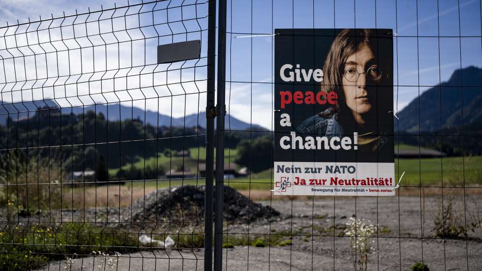 epa13262531 A campaign poster 'Give peace a chance!' with John Lennon's face stands along a road in Epagny, near Fribourg, Switzerland, 25 September 2026. On 27 September 2026, Swiss voters will go to the polls to decide on the popular initiative 'Safeguard Swiss neutrality' (Neutrality Initiative), which calls for stricter limits on international military cooperation and economic sanctions.  EPA/JEAN-CHRISTOPHE BOTT