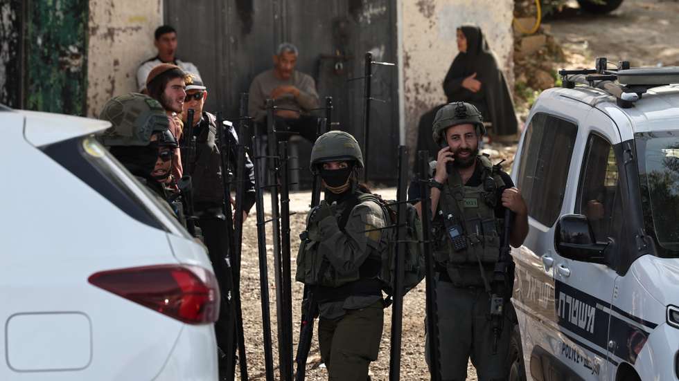 epa13289245 Memeber of the Israeli security and  settlers at Mou’ayad Mahmoud Shop in Al-Lubban Al-Sharqiya  in the West Bank, 08 October 2026, over night Israeli settlers tagged dozens of Israeli flags to block access to Mahmoud shop.  EPA/ATEF SAFADI