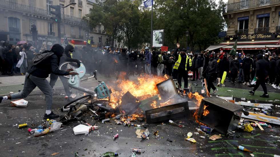 epa13311386 Protesters throw electric bikes into a burning trash bin during a demonstration against rising living costs and cuts to public services in Paris, France, 17 October 2026. The nationwide mobilization brings together Yellow Vest (Gilets Jaunes) activists, high school and university students, trade unions and other groups protesting rising living costs, fuel prices and deteriorating public services, while demanding improvements in education and school conditions.  EPA/YOAN VALAT