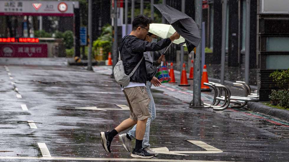 epa13324708 A couple braces against wind and rain under an umbrella while crossing a street during Typhoon Champi in Taipei, Taiwan, 23 October 2026. Typhoon Champi brought heavy rainfall that raised concerns over urban flooding and low road visibility in northern cities.  EPA/CHENG-CHIA HUANG