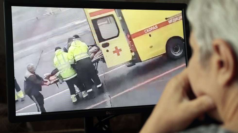 epa08613985 A person (R) in Moscow watches a video on social media showing Russian opposition activist and anti-corruption fund head Alexei Navalny being carried on a stretcher by an ambulance team, in Omsk, Russia, 20 August 2020. Navalny's spokeswoman Kira Yarmysh said on social media on 20 August that the opposition leader and critic of President Vladimir Putin was taken to hospital for alleged poisoning after he started feeling unwell during a flight from Siberia to Moscow. The plane made an emergency landing in the city of Omsk.  EPA/SERGEI CHIRIKOV
