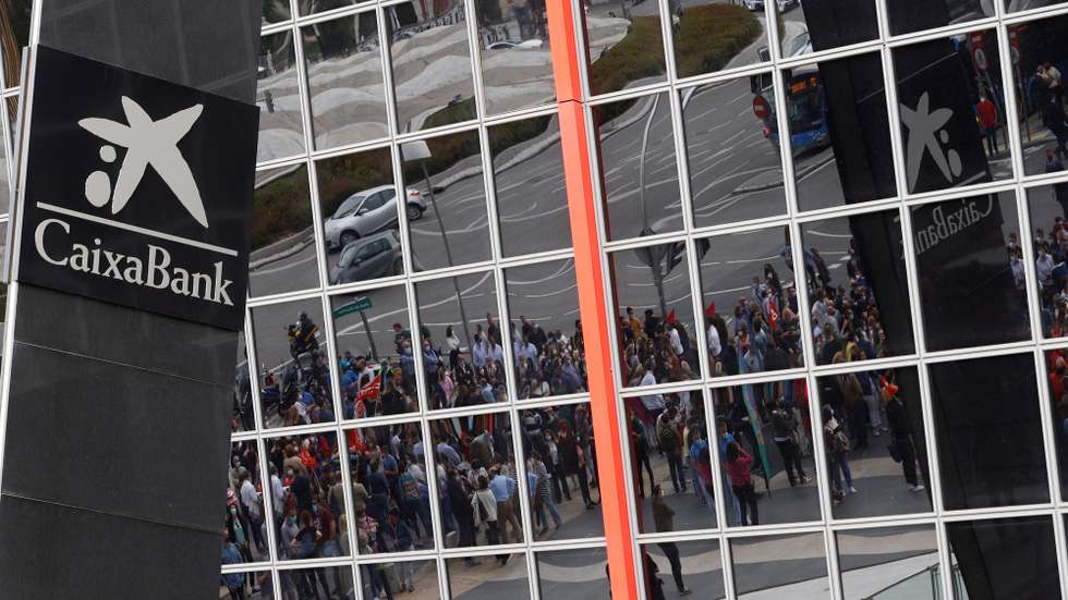 epa09292795 Caixabank workers are reflected on the glass of Caixabank's building during a protest held against the workforce reduction announced by the Spanish bank in Madrid, Spain, 22 June 2021. Caixabank announced, 20 April 2021, a workforce reduction of 8,291 people, a 18.67 percent of all employees, as well as the closure of 1,534 branches across the country after its merge with Bankia.  EPA/J.J. GUILLEN