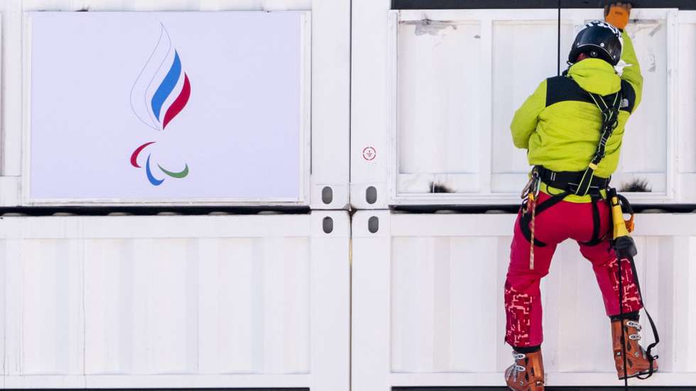 Um homem pendura uma bandeira da Rússia do Comité Paralímpico russo no centro de Ski, na China. 2 de março de 2022