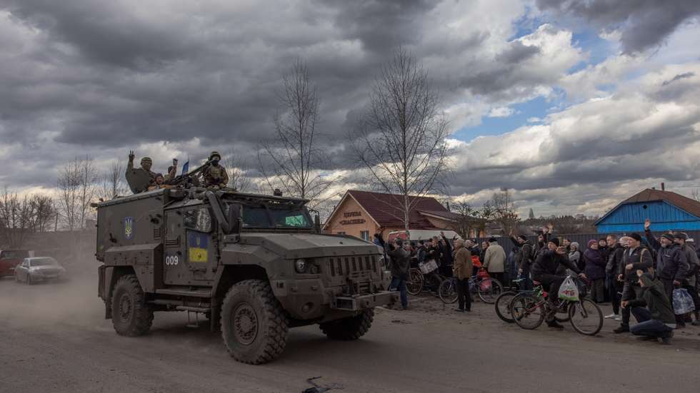 epa09859930 Ukrainian soldiers wave from a military vehicle to local residents waiting in a queue for humanitarian aid, in the recaptured by the Ukrainian army Trostyanets town, in Sumy region, Ukraine, 29 March 2022 (issued 30 March 2022). Trostyanets was recaptured by the Ukrainian army after the town was under Russian forces from the first days of war for over a month. Russian troops entered Ukraine on 24 February prompting the country's president to declare martial law and triggering a series of announcements by Western countries to impose severe economic sanctions on Russia.  EPA/ROMAN PILIPEY