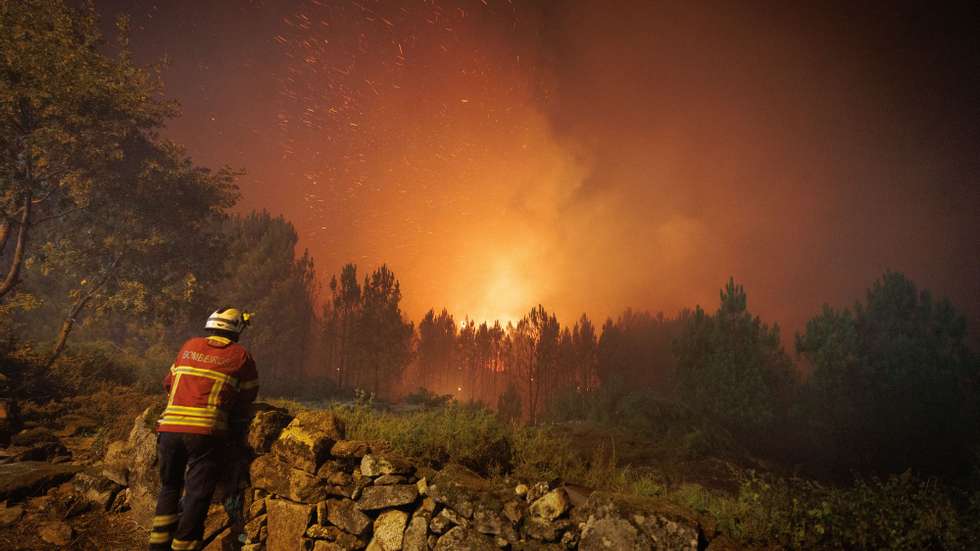 Um bombeiro observa as chamas durante o combate ao incêndio na aldeia de Escariz que se viu envolvida pelas chamas, esta tarde, em Vila Real, 21 de agosto 2022. PEDRO SARMENTO COSTA/LUSA