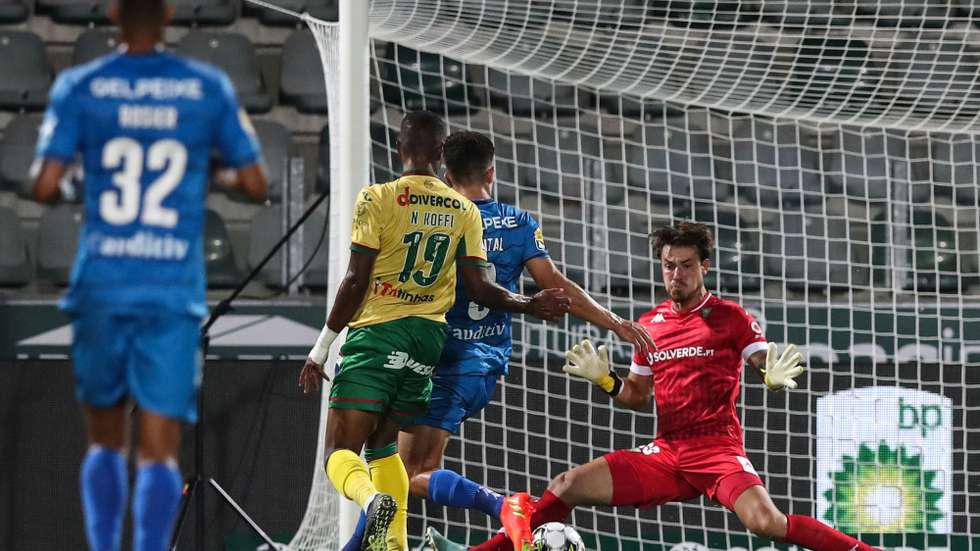 O jogador do Paços de Ferreira Koffi (2-E) disputa a bola com o guarda-redes do Estoril Praia Figueira durante o jogo da Primeira Liga de Futebol, no estádio da Mata Real, em Paços de Ferreira, 26 de agosto de 2022. JOSÉ COELHO/LUSA