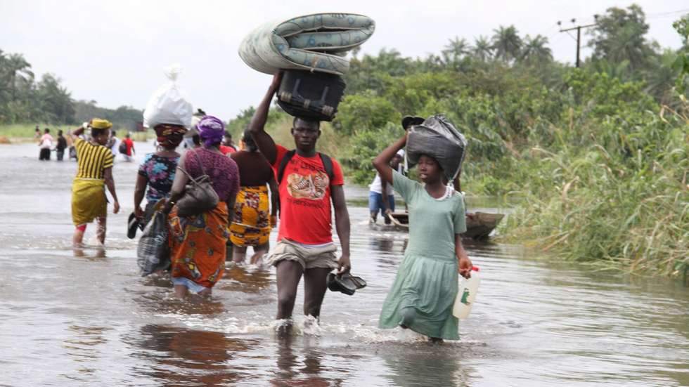 epa03432195 Locals wade through along a flooded road in Ohoror in Ughelli north local government council in the oil rich Niger delta region, Nigeria, 13 October 2012. The floods in the region, which have been the worst in decades, have killed 140 people and left hundreds of thousands homeless. A food crisis is also feared, according to local sources.  EPA/GEORGE ESIRII