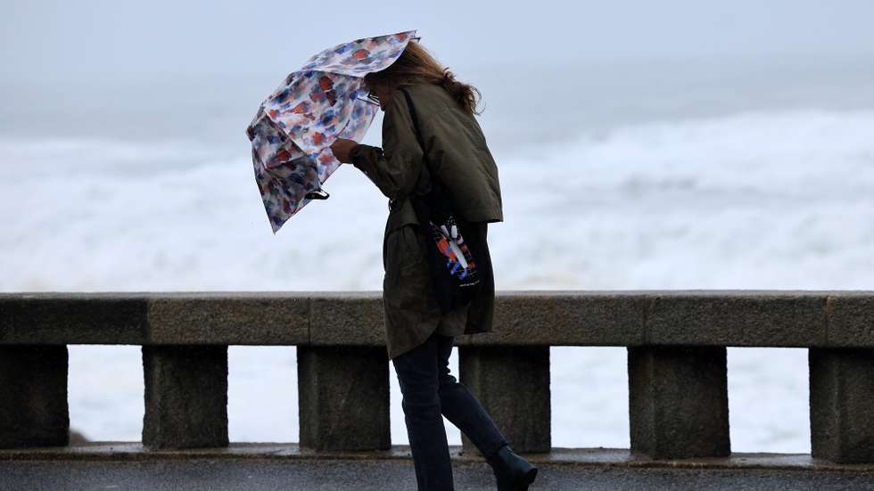 Uma mulher tenta proteger-se da chuva e do vento na marginal da Foz do Douro no Porto, 17 de outubro de 2023. Mais de 40 ocorrências foram registadas desde as 00:00 de hoje, a maioria na Grande Lisboa e em Setúbal, devido ao mau tempo, segundo informação disponível no ‘site’ da Autoridade Nacional de Emergência e Proteção Civil (ANEPC). ESTELA SILVA/LUSA