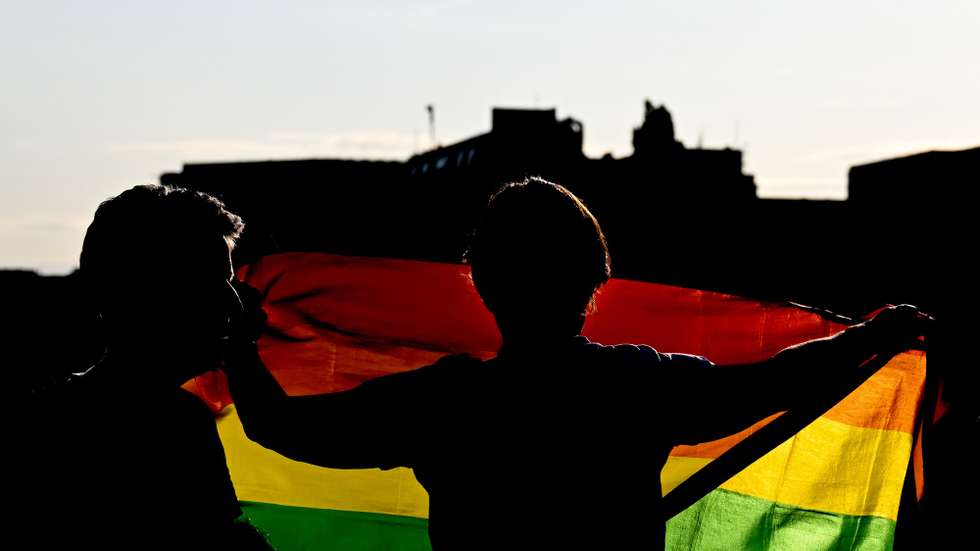 epa10758674 A person holds a rainbow flag while observing participants of the Berlin Canal Pride onboard boats on the Spree River ahead of the 'CSD Berlin 2023' pride parade in Berlin, Germany, 20 July 2023. The 45th Christopher Street Day (CSD) in Berlin takes place on 22 July 2023.  EPA/FILIP SINGER