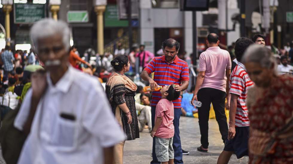 epa10674504 A man gives a drink to his son to cool off as they wait for a train on a hot day, at the Chennai Central Railway Station, in Chennai, India, 05 June 2023.  EPA/IDREES MOHAMMED