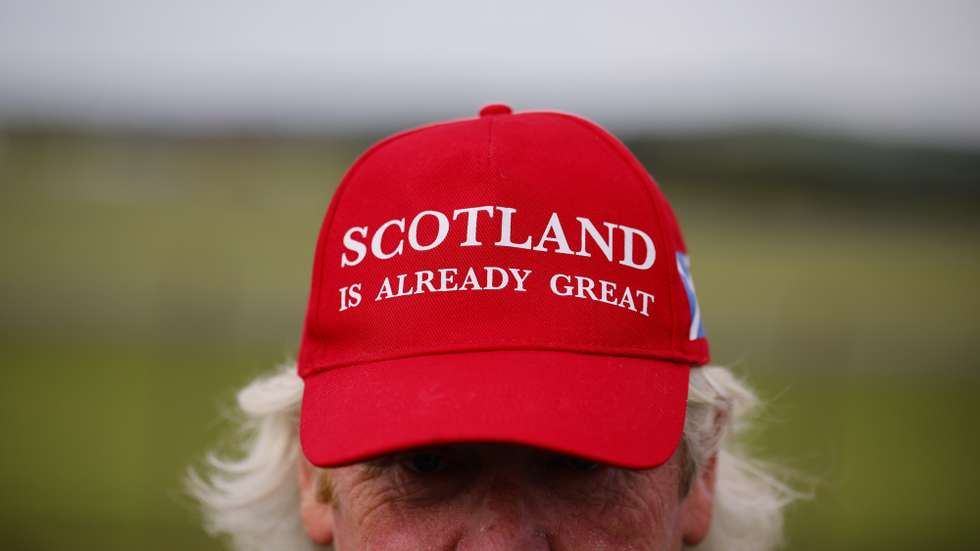 epa12262213 A person wears a 'Scotland is Already Great' hat outside Prestwick Airport ahead of the arrival of the US President in Glasgow, Scotland, Britain, 25 July 2025. President Trump is due to visit Scotland where he will visit his golf courses and meet with UK Prime Minister Keir Starmer.  EPA/TOLGA AKMEN