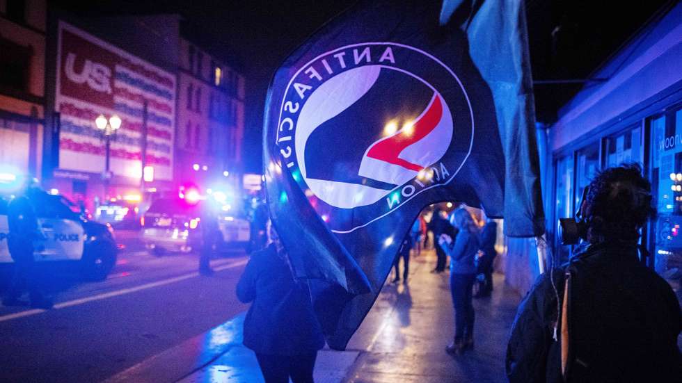 epa08799778 An Antifascist Action (Antifa) flag is seen during a protest following the US presidential election in Portland, Oregon, USA, 04 November 2020. Portland Police declared a riot after protesters began damaging businesses.  EPA/CHRISTIAN MONTERROSA