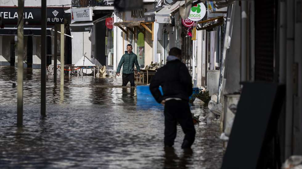 Populares caminham dentro de água numa zona inundada pelas cheias, na zona ribeirinha de Alcácer do Sal, Setúbal, 06 de fevereiro de 2026. Treze pessoas morreram em Portugal desde a semana passada na sequência da passagem das depressões Kristin e Leonardo, que provocaram também muitas centenas de feridos e desalojados.. JOSÉ SENA GOULÃO/LUSA