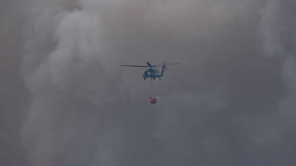 epaselect epa12935618 A police helicopter equipped with a water bucket responds to a forest fire in Jozefow, eastern Poland, 06 May 2026. Since 05 May afternoon, firefighters have been battling a forest fire in the Jozefow Forest District, Bilgoraj County, that has spread to approximately 250 hectares. During the operation, a Dromader firefighting aircraft crashed, killing the pilot.  EPA/WOJTEK JARGILO POLAND OUT