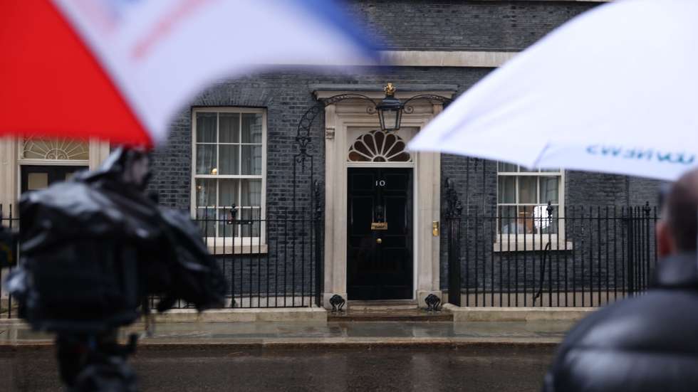 epa12957953 Members of the media shelter under umbrellas outside 10 Downing Street, the official residence and office of the prime minister, in London, Britain, 14 May 2026. British Prime Minister Starmer is under pressure after some junior ministers and the Health Minister resigned. MPs in his own party have called for him to stand down, or establish a timetable for his departure, in reaction to poor local election results.  EPA/NEIL HALL