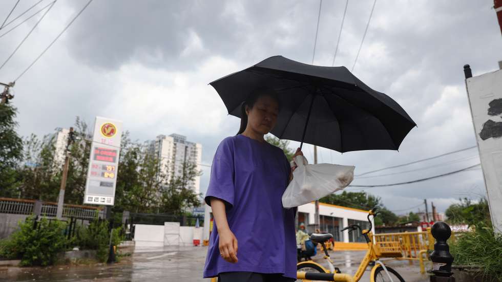 epa13155246 A woman walks in the rain in Beijing, China, 07 August 2026. The Municipal Meteorological Observatory issued multiple yellow storm alerts on Friday 07 August as the city was hit by heavy rain and thunderstorms.  EPA/WU HAO