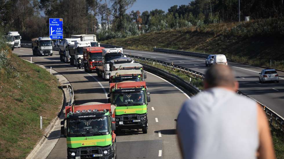Populares observam a passagem dos camiões pesados em marcha lenta do setor das terraplanagens contra o aumento dos combustíveis, em Aveiro, 25 de setembro de 2026. Promovida por um movimento de empresas de extração de materiais, terraplenagem e escavação, movimentação e transporte de terras e inertes em protesto contra o aumento do preço gasóleo e o “tratamento discriminatório por parte do Governo”. Reúne quase 100 empresas e cerca de 500 camiões pesados. JOSÉ COELHO/LUSA
