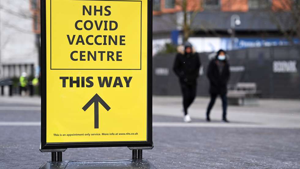 epa09001299 People walk past a sign to a Covid-19 vaccination centre in London, Britain, 10 February 2021. British Vaccines Minister Nadhim Zahawi has stated he was confident the NHS would be able to reach the target of immunising all those over the age of fifty by May. Some twelve million people across the UK have already received their first dose of a Covid-19 vaccine.  EPA/ANDY RAIN
