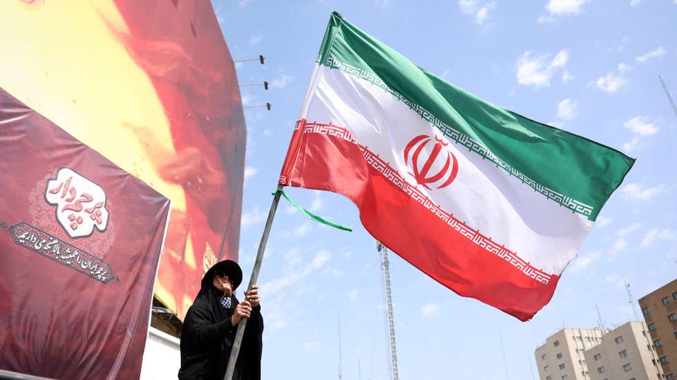 epa13175371 An Iranian woman flies Iran's national flag at the Valiasr square in Tehran, Iran, 17 August 2026.  Iranian Army chief Amir Hatami announced a 30,000 US dollar bounty for killing or capturing US military personnel, offering double the reward for Iranian women who carry out the action, according to Iranian state media.  EPA/ABEDIN TAHERKENAREH RESTRICTIONS: NO Access Israel Media/Persian Language TV Stations Outside Iran/Strictly No Access BBC Persian/VOA Persian/Manoto TV/Iran International TV. (As mandated by Iran's Directorate General for Foreign Media) --