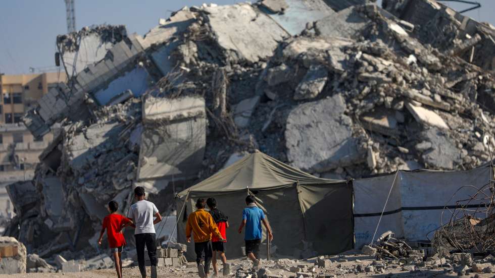 epa12488117 Palestinian children walk next to the rubble of destroyed buildings in Gaza City, Gaza Strip, 28 October 2025, amid a ceasefire between Israel and Hamas. Following Israeli claims that Hamas violated the ceasefire, Prime Minister Netanyahu ordered military strikes on the Gaza Strip on 28 October. In response, Hamas announced it was postponing the planned handover of a recovered hostage's body, citing Israeli truce violations.  EPA/MOHAMMED SABER
