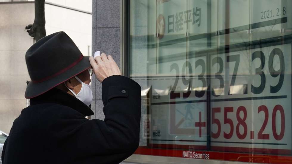 epa08995552 A pedestrian looks at a display showing Nikkei Stock Average during the afternoon trading session in Tokyo, Japan, 08 February 2021. Tokyo stocks climbed over 29,000 level for the first time in more than 30 years. The benchmark Nikkei Stock Average surged 609.31 points, or 2.12 per cent, to close at 29,388.50 on hope that US government may implement a new economic package for a breakthrough against the new coronavirus pandemic.  EPA/KIMIMASA MAYAMA