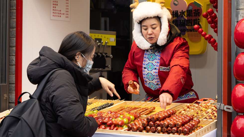 epa12582217 A person buys tanghulu in Beijing, China, 10 December 2025. The National Bureau of Statistics (NBS) of China reported that China’s annual inflation rate rose to 0.7 percent in November from 0.2 percent in October, reaching the highest level since March 2024.  EPA/JESSICA LEE