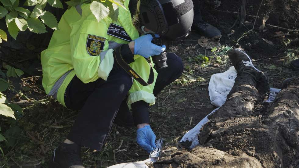 epa10174213 Ukrainian policemen exhume the bodies of two civilians, who were killed during the occupation of that territory by Russian troops, which was retaken by Ukrainian troops two days ago, in the village of Grakovo in Kharkiv's surroundings, Ukraine, 09 September 2022. Kharkiv and surrounding areas have been the target of heavy shelling since February 2022, when Russian troops entered Ukraine starting a conflict that has provoked destruction and a humanitarian crisis.  EPA/VASILIY ZHLOBSKY