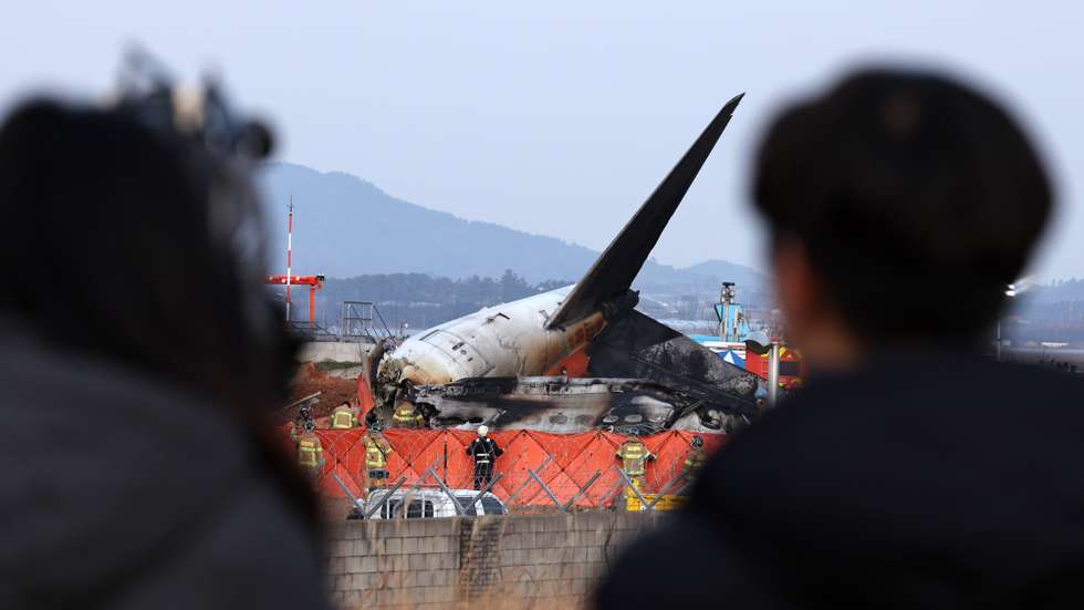 epaselect epa11797046 People look on as firefighters search at the wreckage of the Jeju Air aircraft at Muan International Airport in Muan, 288 kilometers southwest of Seoul, South Korea, 29 December 2024. According to the National Fire Agency, a passenger jet carrying 181 people erupted in flames after going off the runway at an airport in South Korea's southwestern county of Muan on 29 December, leaving at least 176 people dead.  EPA/HAN MYUNG-GU