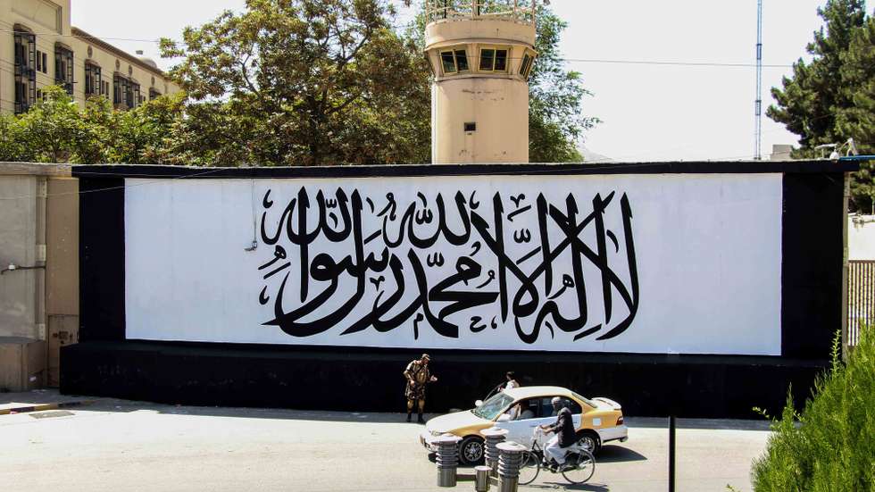 epa09455301 Taliban stand guard outside the building of former US embassy as the wall painted with text in Arabic "There is not God but Allah, Muhammad is the messenger of Allah' in Kabul, Afghanistan, 08 September 2021. Hundreds of protesters on 08 September, came out on the streets of cities across Afghanistan to demand their rights, a day after the Taliban officially announced the formation of a new government consisting exclusively of fundamentalists from their ranks.  EPA/STRINGER