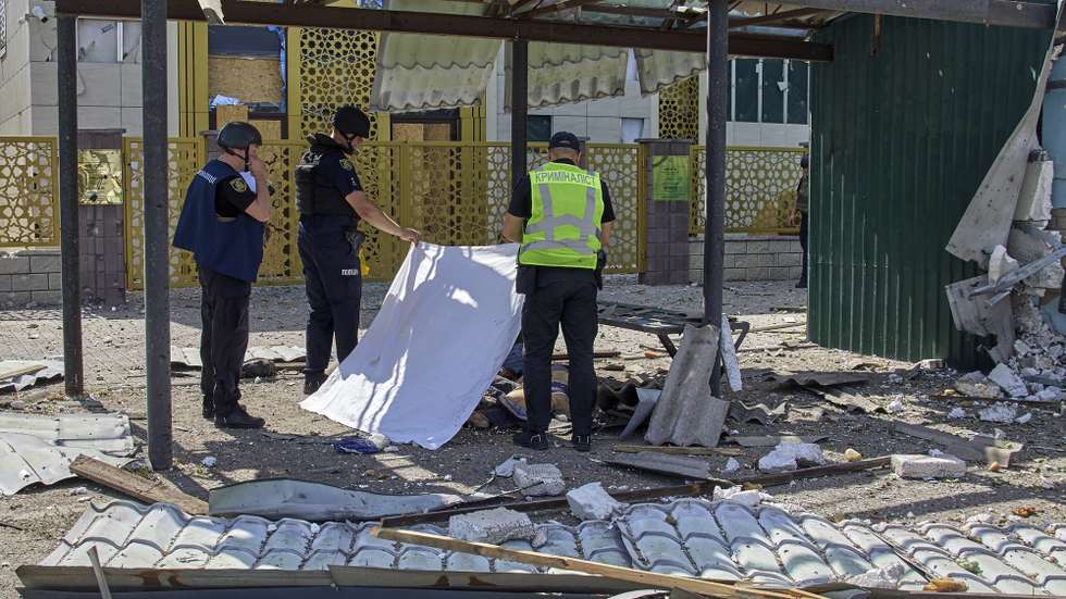 epa10082083 Police officers cover the bodies of victims at a bus stop following a Russian rocket strike in Kharkiv, Ukraine, 20 July 2022. At least three people were killed, including a 13-year-old, and two injured in the attack, according to the State Emergency Service. Kharkiv and surrounding areas have been the target of heavy shelling since February 2022, when Russian troops entered Ukraine starting a conflict that has provoked destruction and a humanitarian crisis.  EPA/SERGEY KOZLOV