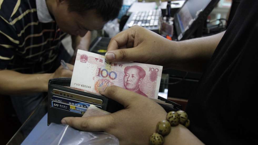 epa04881886 A Chinese customer at the front of a queue shows this photographer a 100 Chinese Yuan, or Renminbi, bill at a convenience store in Beijing, China, 13 August 2015. China's central bank on 13 August devalued the yuan for the third time in three days, to aid a slowing economy. The People's Bank of China unexpectedly adjusted its daily reference exchange rate by a further 1.1 per cent, setting it at 6.4010 to the US dollar.  EPA/ROLEX DELA PENA