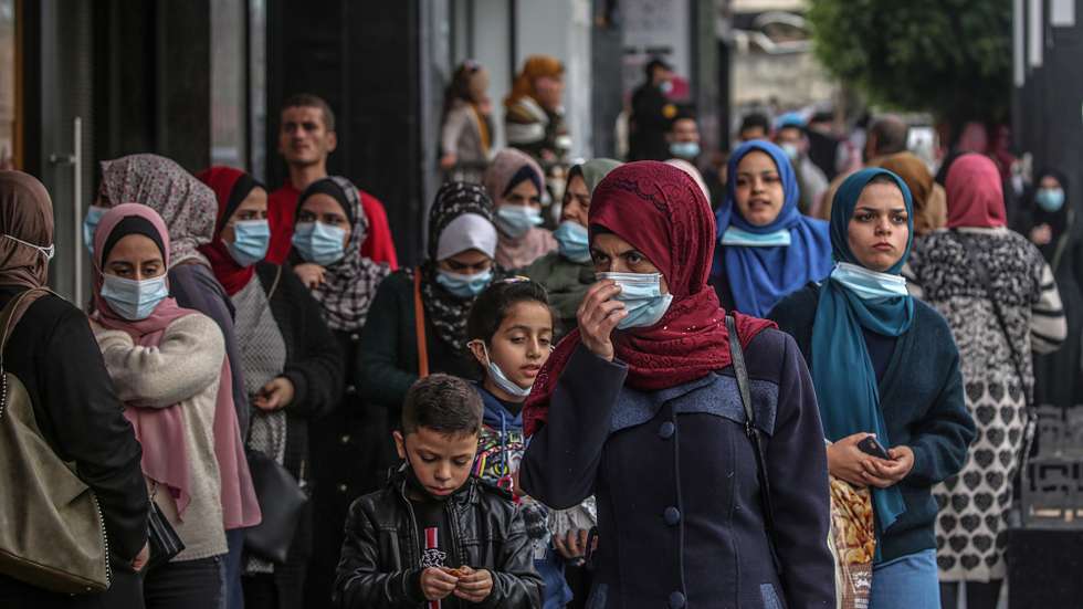 epa08867655 Palestinians wearing protective face masks walk in the market amid the ongoing coronavirus COVID-19 pandemic in Gaza City, 06 December 2020. The Ministry of Interior in Gaza City announced new measures as the number of new infections with the coronavirus increases, which are the closure of schools, universities, mosques, and government ministries until further notice, and work from six in the morning until six in the evening only, and a comprehensive closure on Friday and Saturday of every week.  EPA/MOHAMMED SABER