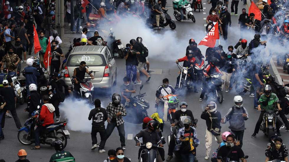 epa09403430 Anti-government protesters react as police fire tear gas at the during a march on the road to prime minister's house in Bangkok, Thailand, 07 August 2021. Hundreds of demonstrators took part a protest of the government at the Democracy Monument and the machine moved to near the prime minister's house area, for to press their demands for resignation of the Thai prime minister, under the declaration of an emergency situation to control the disease amid a surge of COVID-19 cases.  EPA/NARONG SANGNAK