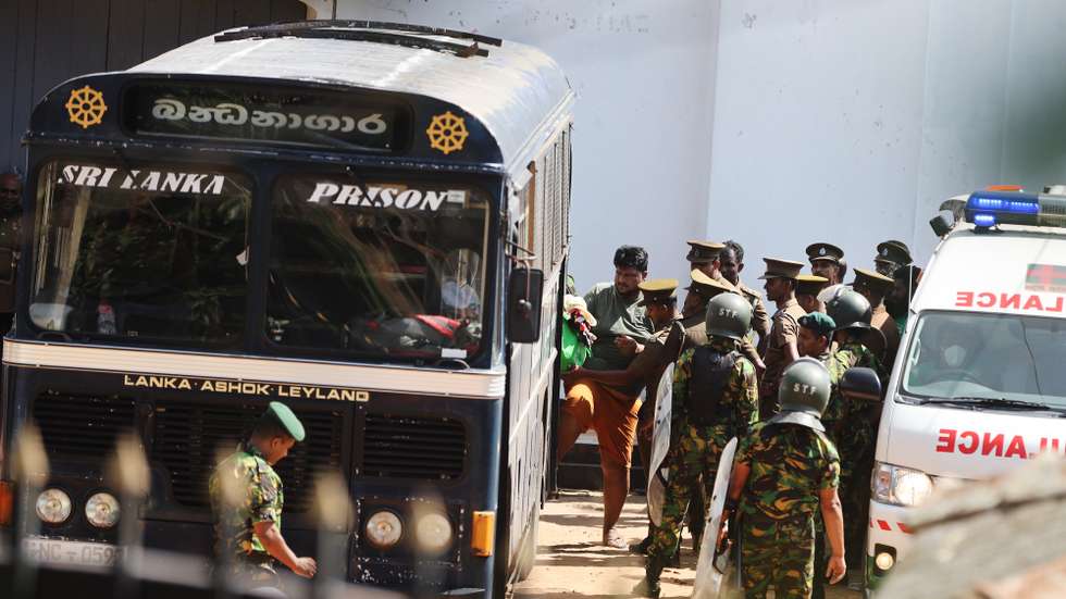 epa13091569 Security personnel escort prisoners to a bus at Negombo Prison on the outskirts of Colombo, Sri Lanka, 06 July 2026. Clashes at the prison have killed 25 people, including four prison guards, and wounded more than 100 following overnight clashes between inmates from two drug gangs at the area's main prison, according to police officials.  EPA/STRINGER
