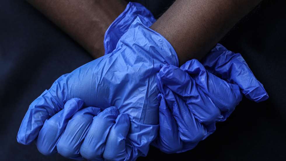 epaselect epa08893189 An Indian security person wearing protective hand gloves stands guard as the health worker (not seen) collects swab samples for a coronavirus COVID-19 Rapid Antigen detection tests from passengers coming from other states of India to Mumbai, at Dadar Terminus in Mumbai, India, 19 December 2020. India, the world's second-hardest hit nation by the coronavirus disease (COVID-19) pandemic, has crossed the 10-million mark of infections as the country awaits several emergency vaccines to be approved.  EPA/DIVYAKANT SOLANKI