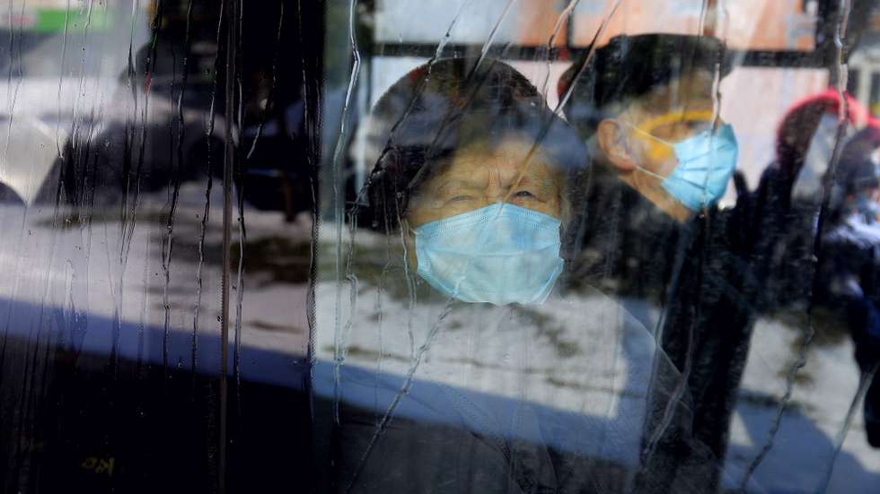 epa09067627 A Romanian elderly woman that wears a protective mask looks trough a bus window during cold weather, in Bucharest, Romania, 11 March 2021. A wave of late snowfalls and mild blizzards reached southern and central Romania.  EPA/ROBERT GHEMENT