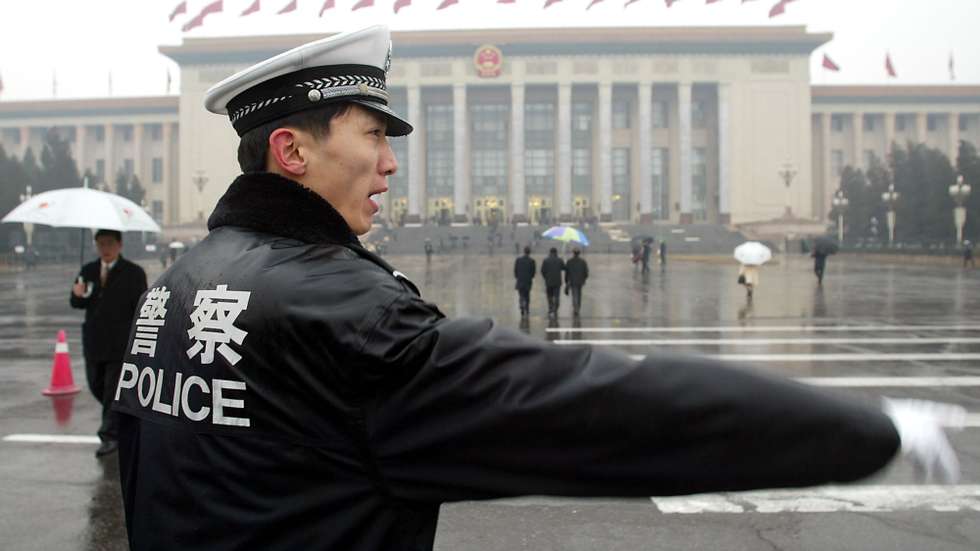 A Chinese policeman directs traffic outside the Great Hall of the People prior to a plenary session of the National People's Congress (NPC) in Beijing 11 March 2003.  China arrested 3,402 people for endangering state security last year, as the fight to wipe out separatism, terrorism and religious extremism was stepped-up.                               AFP PHOTO/GOH Chai Hin