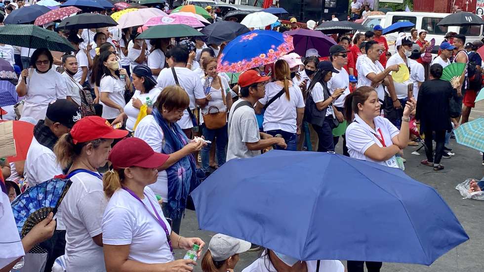 epa10766365 Filipinos hold umbrellas as they watch a street performance in Quezon city, Metro Manila, Philippines, 24 July 2023. State weather forecast hoisted Tropical Cyclone wind signal warnings in main island Luzon including Metro Manila due to Typhoon Doksuri as it is forecast to make landfall either in Batanes island or Cagayan province.  EPA/FRANCIS R. MALASIG